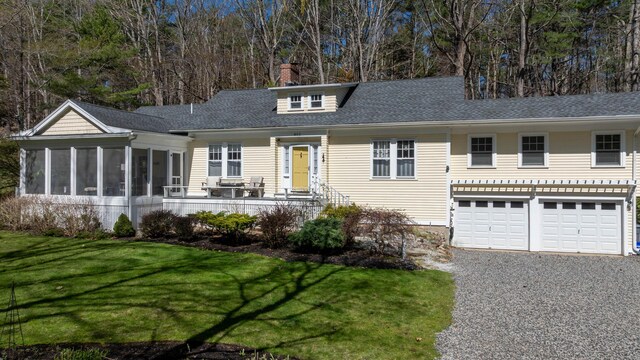 ranch-style home with driveway, a sunroom, a front lawn, an attached garage, and a shingled roof