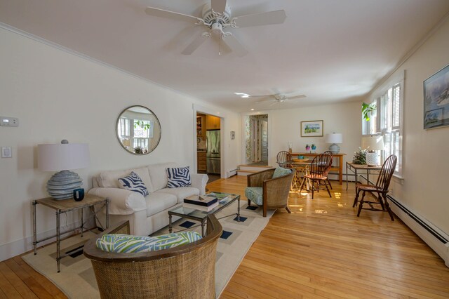 living area featuring ceiling fan, a baseboard heating unit, ornamental molding, and light wood-style floors