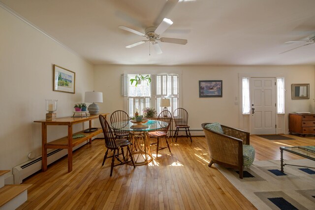 dining space with crown molding, ceiling fan, a baseboard heating unit, and light wood-type flooring