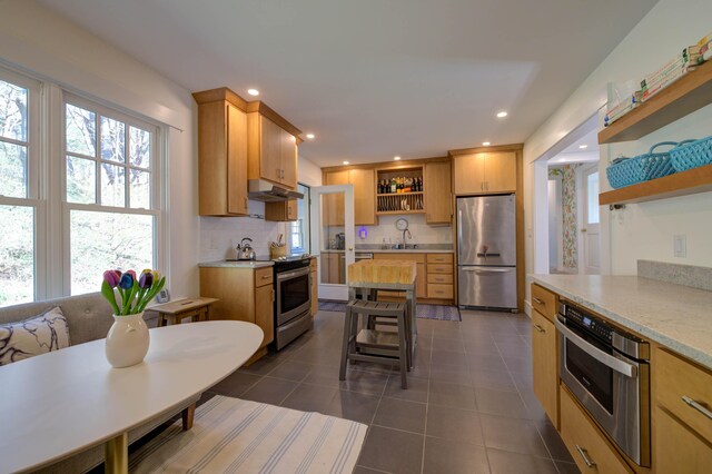 kitchen featuring dark tile patterned floors, open shelves, a sink, under cabinet range hood, and stainless steel appliances