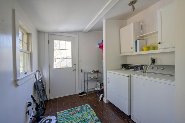 laundry area featuring washing machine and clothes dryer, dark tile patterned flooring, and cabinet space