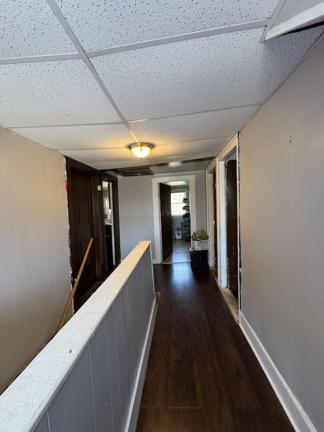 hall featuring dark wood finished floors and a drop ceiling