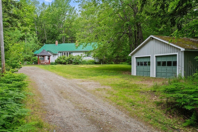95 Hatcase Pond Rd, Eddington, ME 04428 - view of front of house with a chimney, an outdoor structure, a garage, a front lawn, and a metal roof