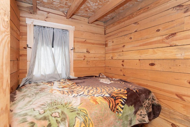 bedroom featuring beamed ceiling and wood walls