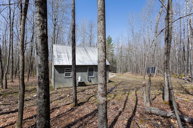 view of side of home featuring metal roof and an outdoor structure