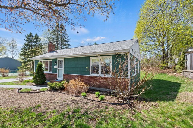 18 Grant St, Sanford, ME 04083 - view of front of property with brick siding, a chimney, a shingled roof, and a front lawn