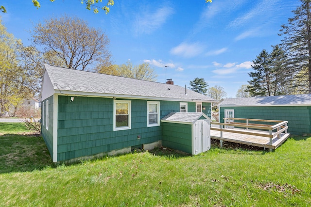 18 Grant St, Sanford, ME 04083 - back of property featuring a chimney, roof with shingles, a lawn, a deck, and a storage shed