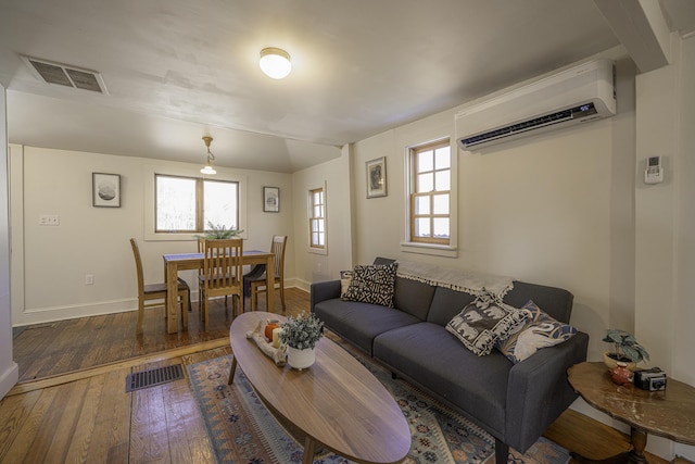 living room with visible vents, baseboards, a wall mounted AC, and hardwood / wood-style flooring