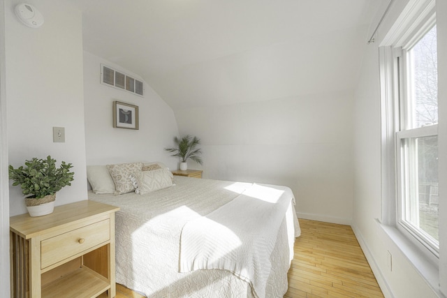 bedroom featuring visible vents, light wood finished floors, and lofted ceiling