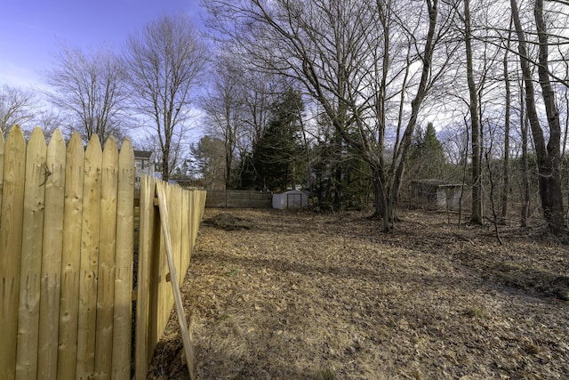 view of yard featuring an outdoor structure, fence, and a shed