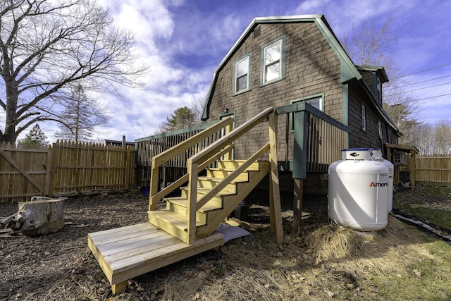 back of house with fence, a gambrel roof, and stairway