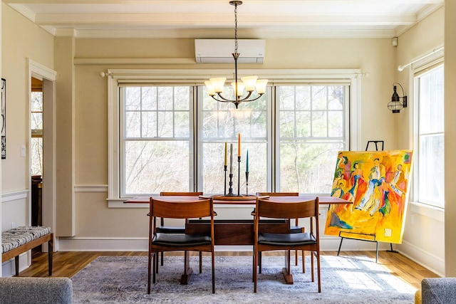 dining area featuring an AC wall unit, crown molding, wood finished floors, and an inviting chandelier