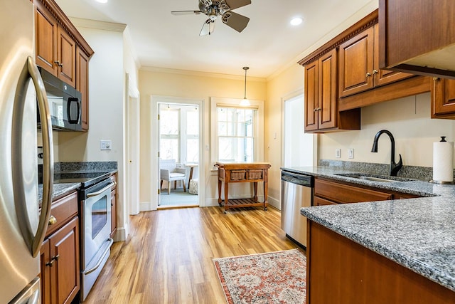 kitchen with brown cabinets, ceiling fan, a sink, stainless steel appliances, and light wood-type flooring