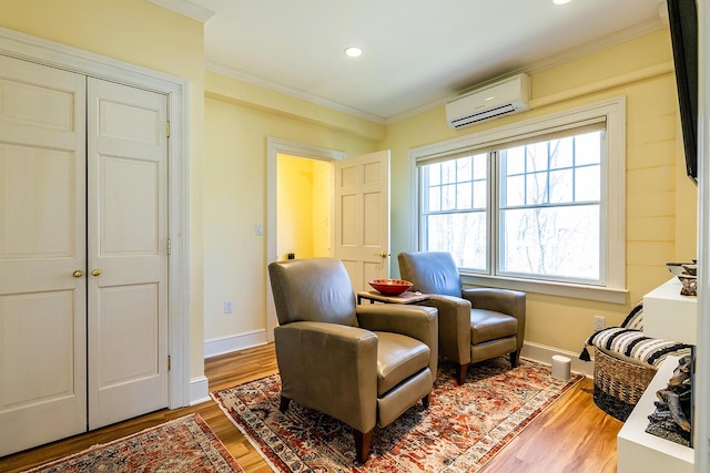 living area featuring crown molding, an AC wall unit, recessed lighting, baseboards, and wood finished floors