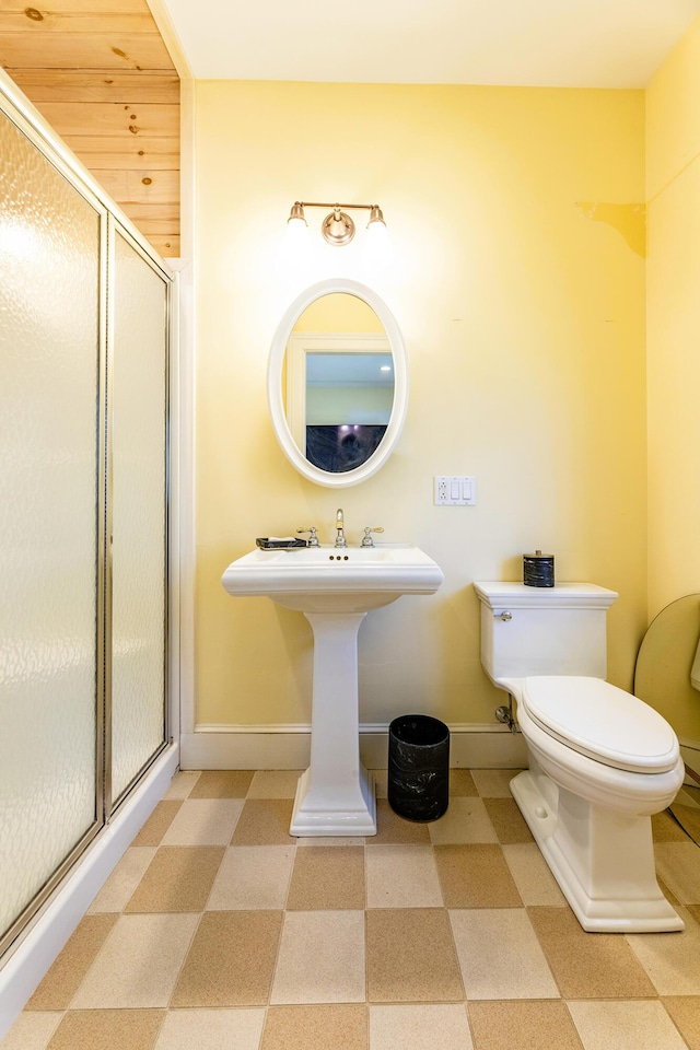 bathroom featuring toilet, tile patterned floors, a shower stall, and baseboards