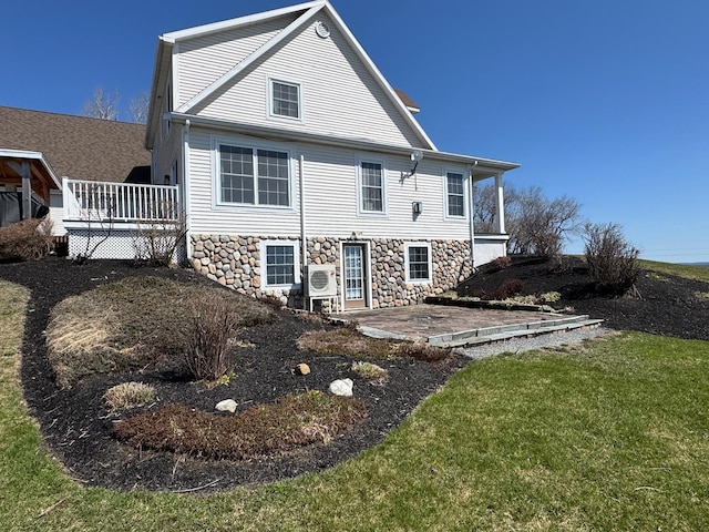 129 Williams Rd, Presque Isle, ME 04769 - back of house featuring ac unit, stone siding, a wooden deck, a patio area, and a lawn