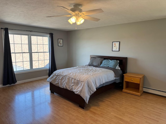 129 Williams Rd, Presque Isle, ME 04769 - bedroom with a textured ceiling, baseboard heating, baseboards, and light wood-type flooring