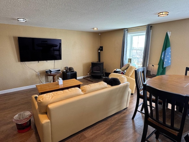129 Williams Rd, Presque Isle, ME 04769 - living area featuring a wood stove, a textured wall, baseboards, a textured ceiling, and wood finished floors