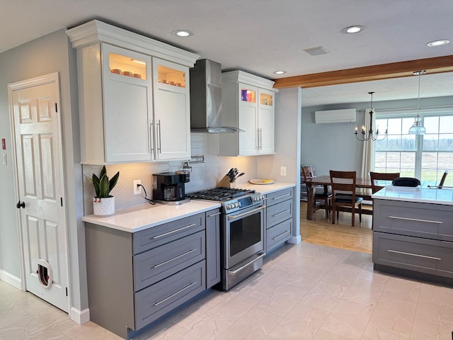 129 Williams Rd, Presque Isle, ME 04769 - kitchen with light countertops, an inviting chandelier, gas stove, wall chimney exhaust hood, and gray cabinets