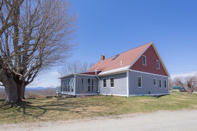 view of side of home with a yard, a chimney, and a sunroom