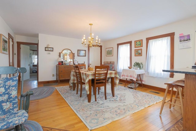 dining area with light wood-style floors, baseboards, visible vents, and a chandelier