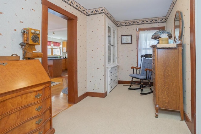 living area with baseboards, wallpapered walls, and light colored carpet