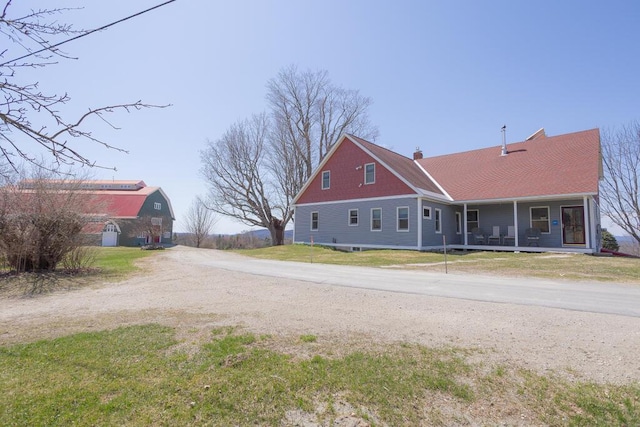 view of front facade featuring dirt driveway, covered porch, and a front yard