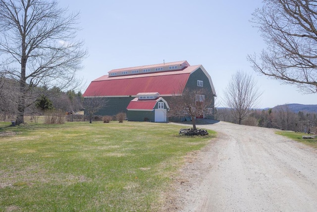 view of barn with a lawn and dirt driveway