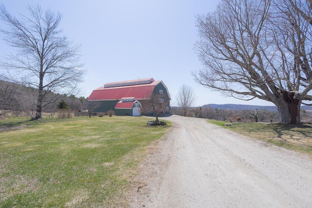 view of road with a barn and dirt driveway