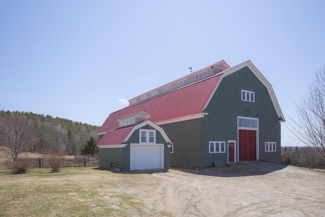 view of barn featuring a garage, fence, and dirt driveway