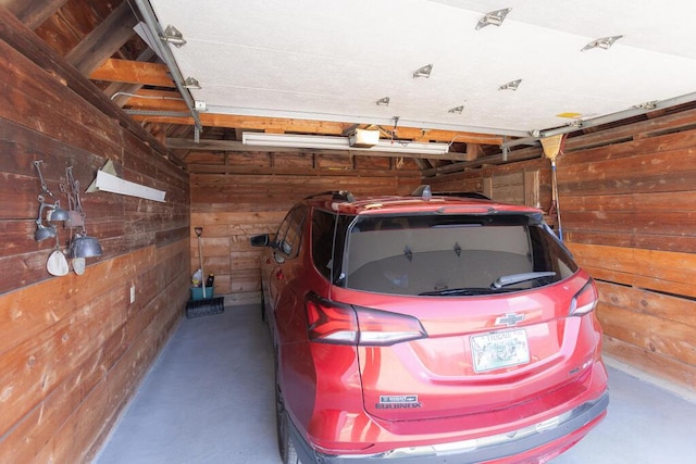 garage with a garage door opener and wood walls