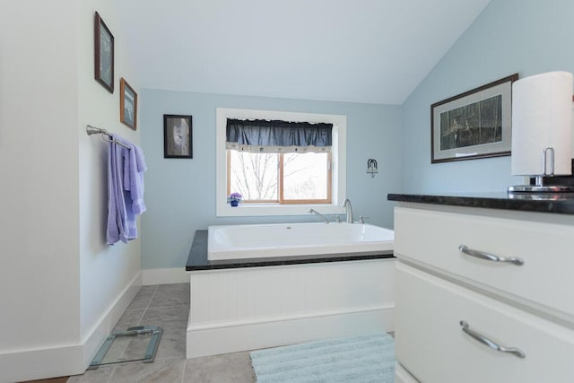 bathroom with baseboards, a bath, tile patterned floors, a sink, and vaulted ceiling