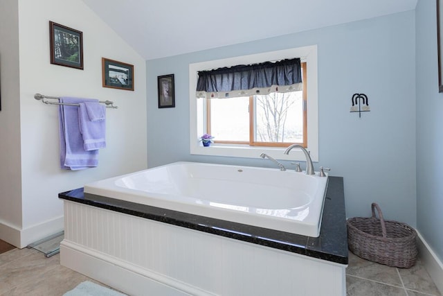 full bathroom with baseboards, a bath, and vaulted ceiling