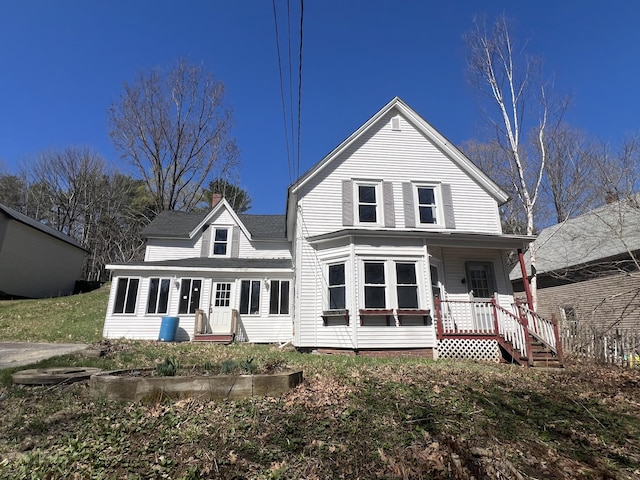 rear view of house featuring a chimney and a porch