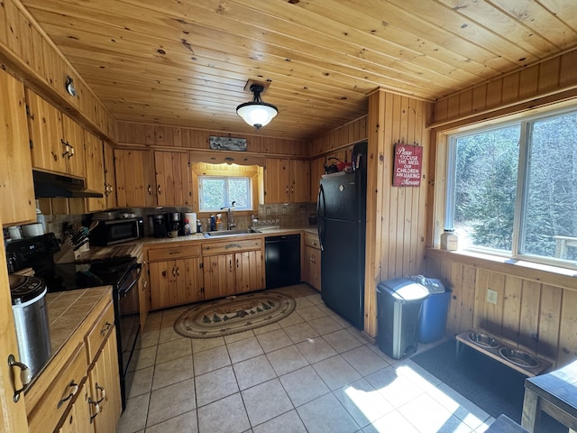 172 Alder Brook Ln, Waltham, ME 04605 - kitchen with tile counters, black appliances, a sink, under cabinet range hood, and wooden walls
