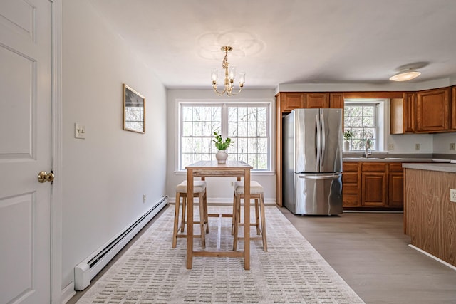 dining space with light wood-style floors, baseboard heating, and a chandelier