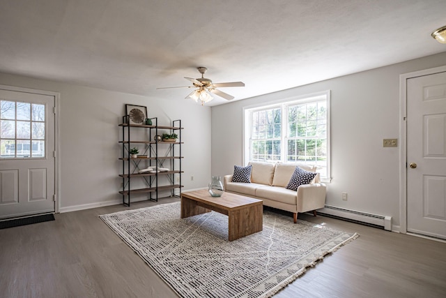 living room with a ceiling fan, a baseboard heating unit, plenty of natural light, and wood finished floors