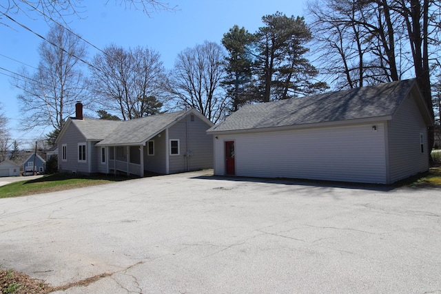 view of front facade with a shingled roof and a chimney