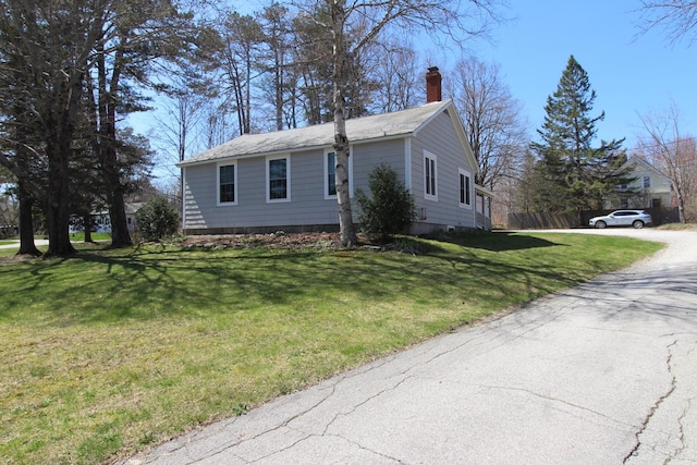 view of front facade with aphalt driveway, fence, a front yard, and a chimney