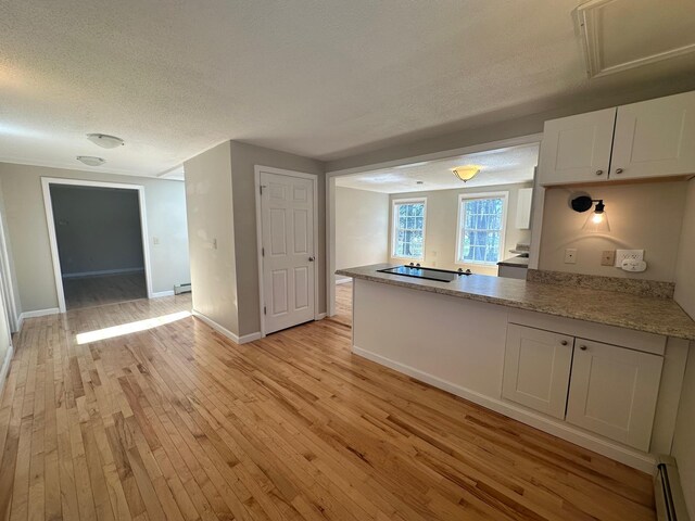 kitchen with baseboard heating, black electric cooktop, a textured ceiling, light wood-style flooring, and a peninsula