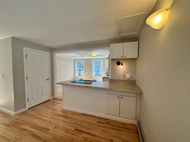 kitchen with a textured ceiling, light wood-type flooring, black electric cooktop, baseboards, and a peninsula