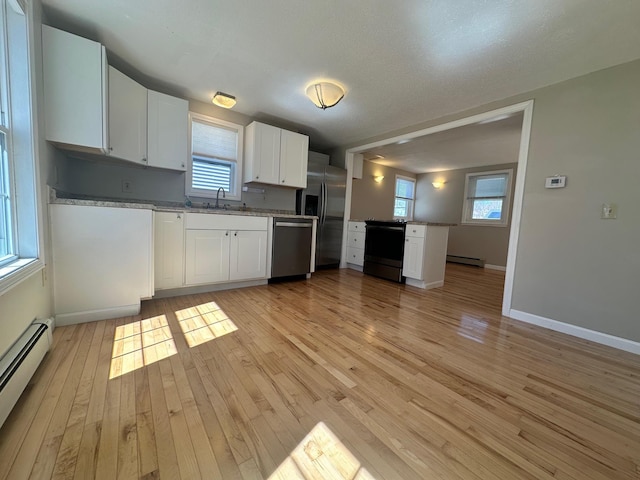 kitchen with white cabinets, baseboard heating, light wood-style floors, stainless steel appliances, and a baseboard heating unit