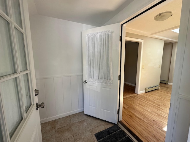 interior space with a baseboard heating unit and a wainscoted wall