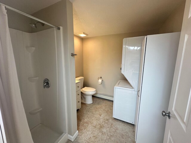 bathroom featuring baseboard heating, tile patterned flooring, vanity, stacked washer and clothes dryer, and a stall shower