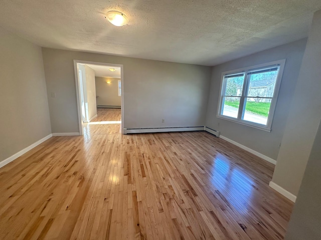 empty room featuring baseboards, a baseboard radiator, light wood-type flooring, and a textured ceiling