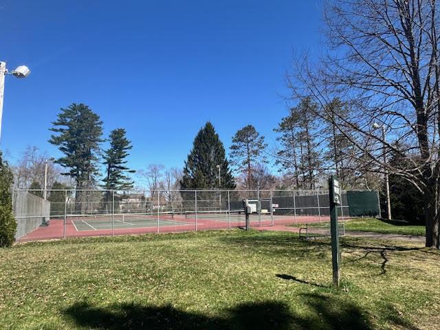 view of sport court featuring fence and a lawn