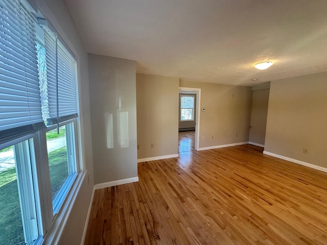 spare room with baseboards, a baseboard radiator, and light wood-style flooring