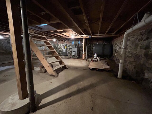 unfinished below grade area featuring water heater, heating fuel, and electric water heater