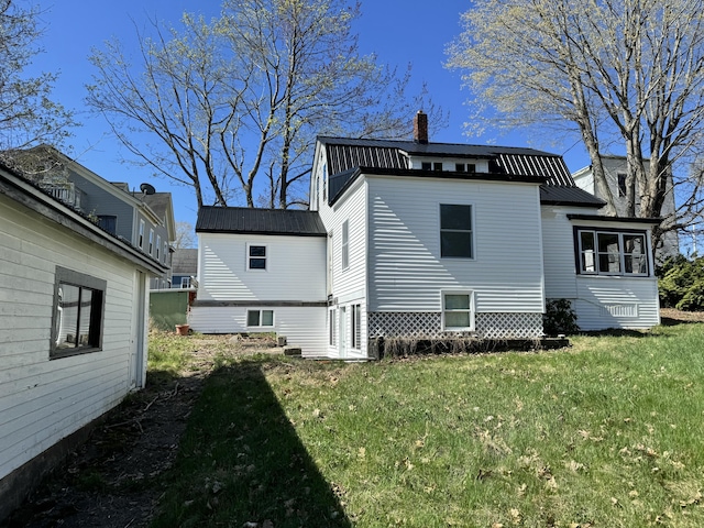 rear view of house featuring a chimney, a yard, a gambrel roof, and metal roof