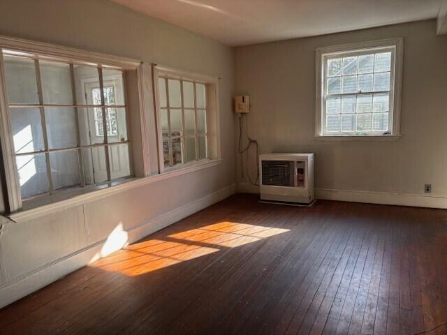 empty room featuring heating unit, baseboards, and hardwood / wood-style floors
